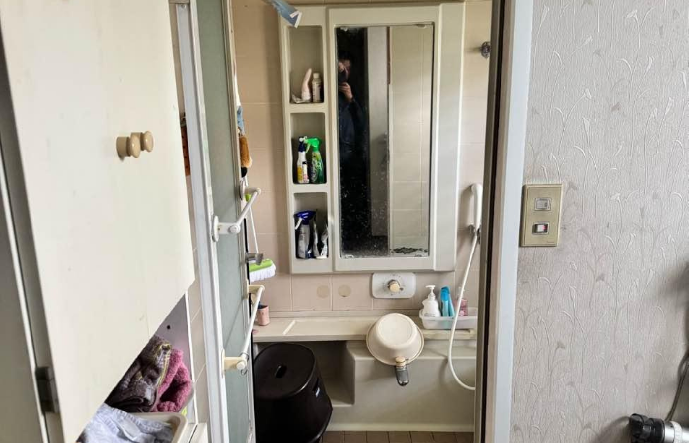 脱衣所から見た改修前の浴室。棚付きの鏡や壁付きの水栓が並ぶ、宮ノ台の住まいの以前の姿