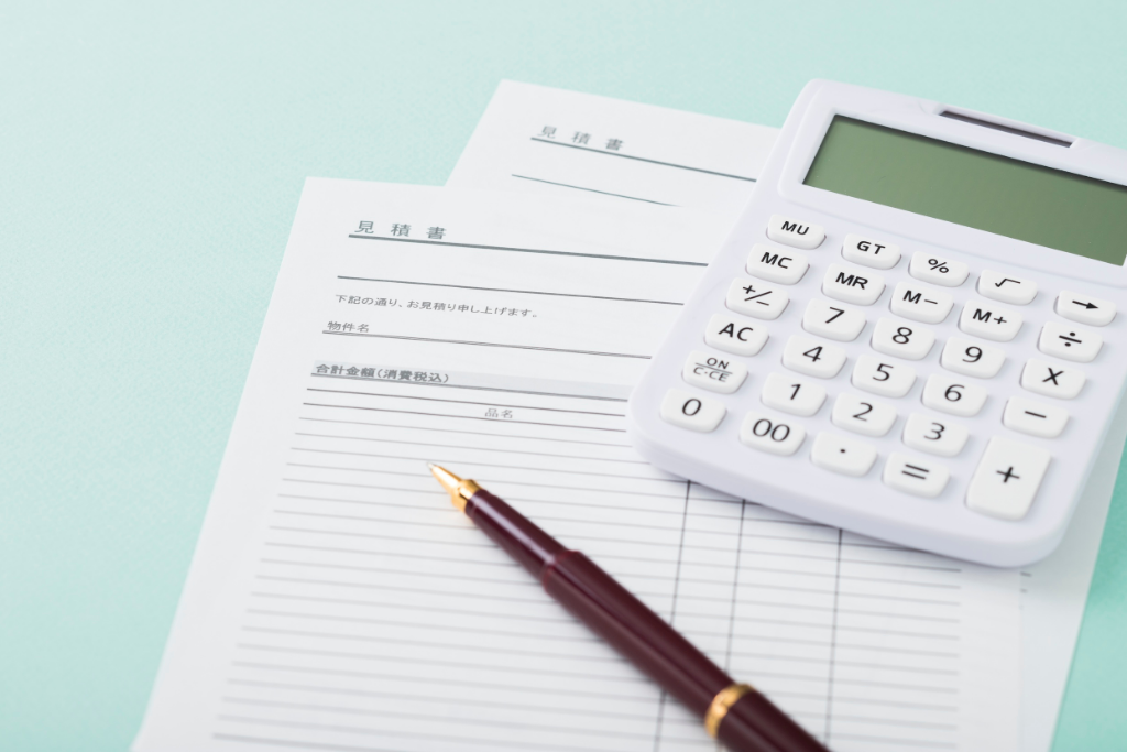 明細の入った書類に電卓とペンを添えて、本体と工事費の総額を確かめる見積もりの場面